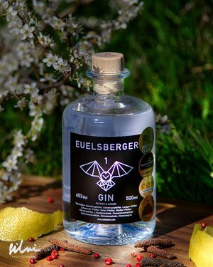Clear glass bottle of Euelsberger Gin 45% ABV 500ml with lemon peels and spices outdoors.