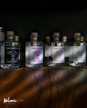 Four Euelsberger gin bottles with distinct labels on a wooden surface against a dark background