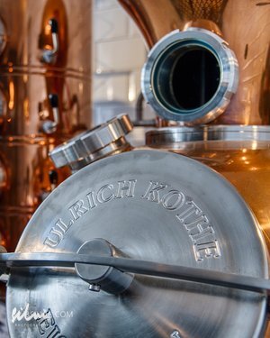 Close-up of a metallic distillation apparatus with engraved circular lid and copper components.