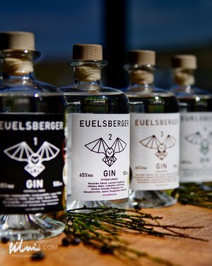 Row of Euelsberger Gin bottles with distinct labels and cork stoppers on a wooden surface.
