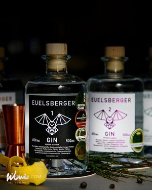Two 500ml EUELSBERGER gin bottles with wooden caps, black and white labels, and cocktail garnishes.