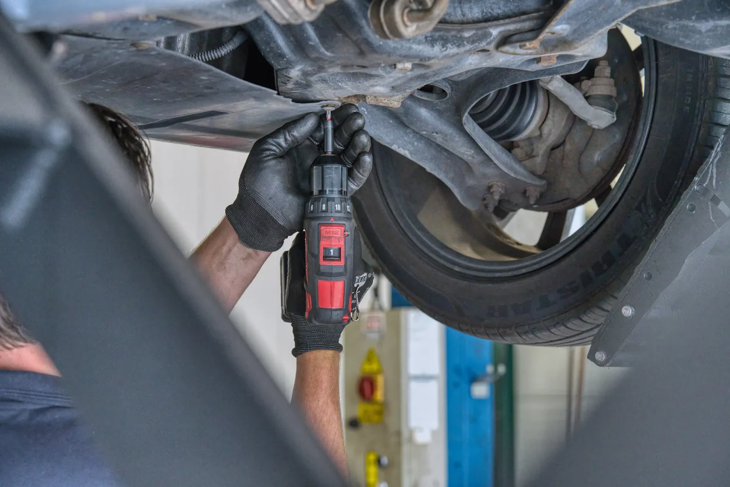 Professional commercial photography showing an automotive technician performing vehicle maintenance.